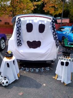 a car with a face painted on the side and decorations around it, sitting in a parking lot next to other cars