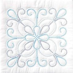 a white quilted pillow with blue and white embroidered designs on the front, sitting on a wooden table