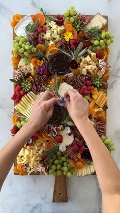 a person is making a fruit and vegetable platter