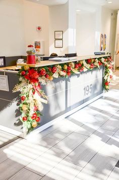 an office decorated for christmas with garland and poinsettis on the front desk