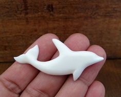 a hand holding a small white plastic dolphin