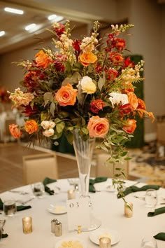 a vase filled with lots of flowers on top of a white table cloth covered table