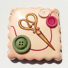 a close up of a button with a pair of scissors and a needle on it