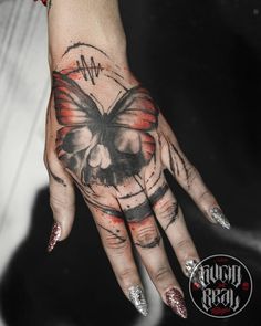 a woman's hand with a butterfly and skull tattoo on the middle of it