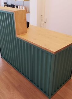 a counter made out of shipping containers sitting on top of a hard wood floor next to a white wall