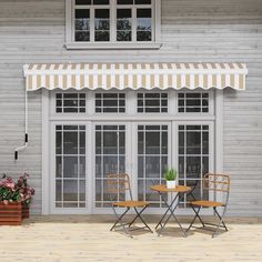 two chairs and a table in front of a building with an awning over it