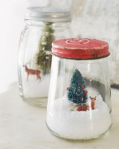 two glass jars filled with snow and christmas ornaments