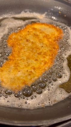 some food is cooking in a frying pan on the stove top with oil and water