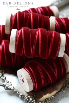 several red spools of thread sitting on top of a silver tray next to a chain