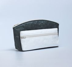 ---------- Description ---------- This makeup/toiletry bag features a minimalist design, crafted from DuPont™ Tyvek®. It includes a larger Dark Green pouch with a wide bottom and crescent-shaped top, and a smaller Snow White pouch with a slim rectangular shape, both secured with a YKK zipper. The smaller, detachable front pouch offers flexible use, allowing you to combine the pouches or use them separately as needed. The larger pouch is ideal for carrying makeup, skincare, and perfume, while the Large Pouch, Unisex Makeup, Toiletry Kit, Bag Makeup, Clutch Pouch, Makeup Organizer, Small Pouches, Toiletry Storage, Travel Pouch