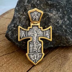 a gold and silver cross sitting on top of a rock