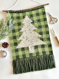 a crocheted christmas tree on a green and white blanket next to other items