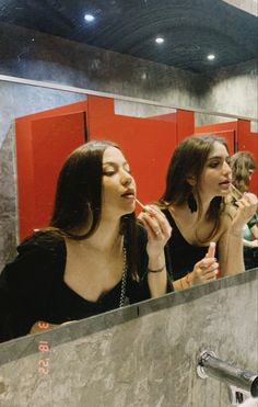 two young women are brushing their teeth in the bathroom mirror while another woman looks on