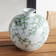 a green and white vase sitting on top of a wooden table