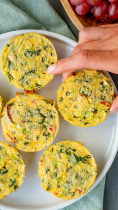 a plate with mini frittatas on it and grapes in the background