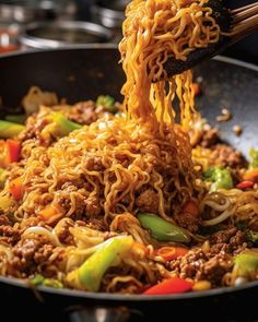 someone is lifting noodles from a wok with chopsticks into the skillet