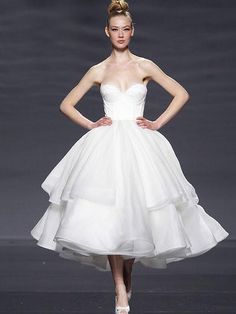 a woman in a white dress is walking down the runway