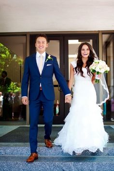 a bride and groom holding hands walking down the steps at their wedding ceremony in front of an entrance