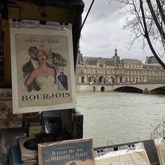 there are many books on the table by the water and buildings in the back ground