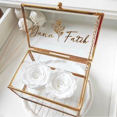 an open box with white flowers inside on a table next to a mirror that says ann and faith