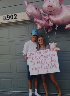 two people standing in front of a garage holding up pink pig balloons and a sign that says, your god said that you can take you to hoo when pigs fly