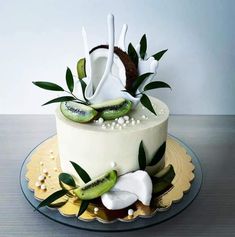 a white cake with kiwi slices and leaves on it