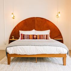 a bed with a wooden headboard and pillows on top of it in a room