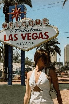 a woman is walking in front of the las vegas sign