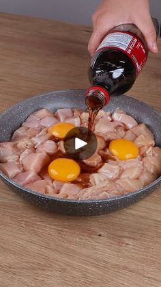 someone is pouring sauce on some food in a pan with eggs and meats inside