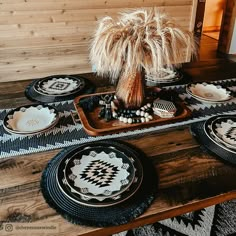 black and white plates on a wooden table with a palm tree in the centerpiece