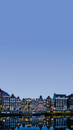 an airplane is flying over the water and buildings in the background at night with lights on