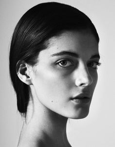 a black and white photo of a woman's face with her hair pulled back