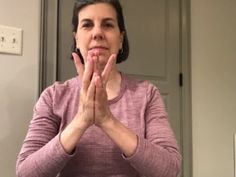 a woman standing in front of a mirror with her hands folded up to the side