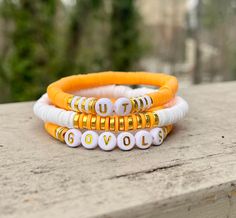 three different colored bracelets sitting on top of a cement slab with trees in the background