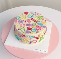 a decorated cake sitting on top of a white table next to a pink and white plate