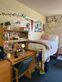 a dorm room with a bed, desk and shelves on the wall next to it