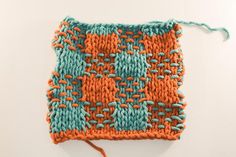 an orange and teal knitted square with two rows of stitches on the side