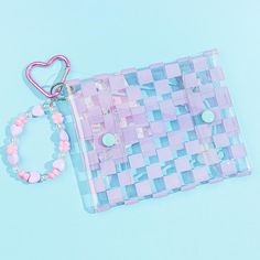 Keep your earphones safe and dry storing them inside this transparent pouch! It has kawaii checkered purple patterns and an illustration of Kuromi harvesting giant flowers. This flat pouch also comes with a bracelet-like charm made from pastel beads. Features top and bottom snap button closures Comes with a heart-shaped carabiner Purple Portable Pencil Case For Gift, Pink Square Pouch For Gift, Purple Rectangular Portable Pouch, Portable Purple Rectangular Pouch, Trendy Purple Pouch For Gift, Trendy Purple Pouch For Gifts, Portable Rectangular Purple Pouch, Trendy Purple Pencil Case For Daily Use, Cute Purple Pencil Case As A Gift