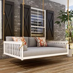 a white porch swing bed with pillows on the front and back cushions hanging from it's sides