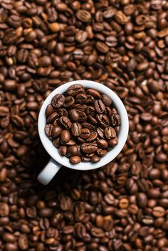 a white cup filled with coffee beans