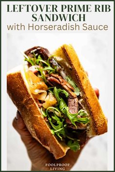 a hand holding a sandwich with meat and vegetables on it, in front of a white background text reads leftover prime rib sandwich with horseradish sauce