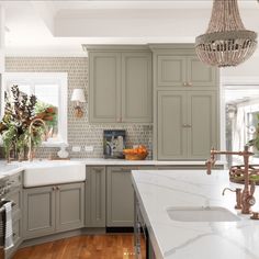 a large kitchen with gray cabinets and white counter tops, an island in the middle