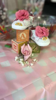 three pairs of shoes with flowers on them sitting on top of a pink and white checkered table cloth