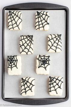 halloween cookies decorated with icing and spider webs on a cookie sheet in a baking pan