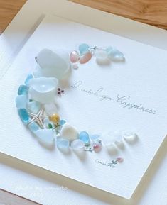 a greeting card with sea glass and seashells arranged in the shape of a heart