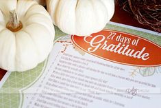 two white pumpkins sitting on top of a paper with the words, 25 days of gratitude