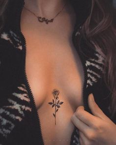 a woman's chest with a rose tattoo on her left side and an open zippered jacket