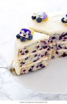 a cake with white frosting and blueberries on top is cut in half to show the inside