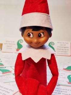 an elf doll sitting on top of a pile of paper