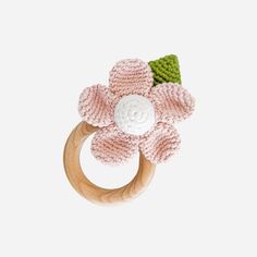 a crocheted wooden ring with a pink flower on the front and green leaves on the back